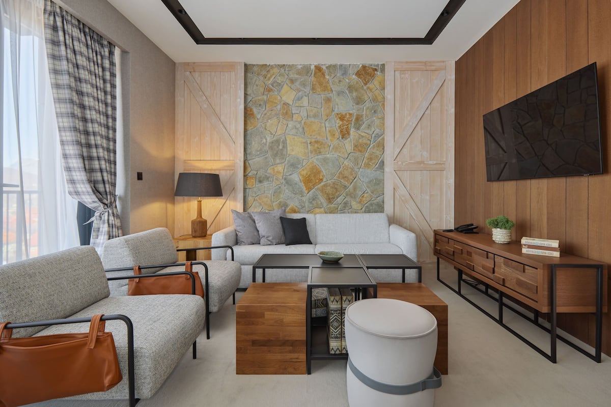 A modern living room with a sofa, coffee table, and a TV mounted on the wall.