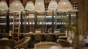 A restaurant interior with multiple tables and chairs, a wine rack in the background, and hanging wicker lamps. - Wulfenia Hotel & Spa (Kolašin)