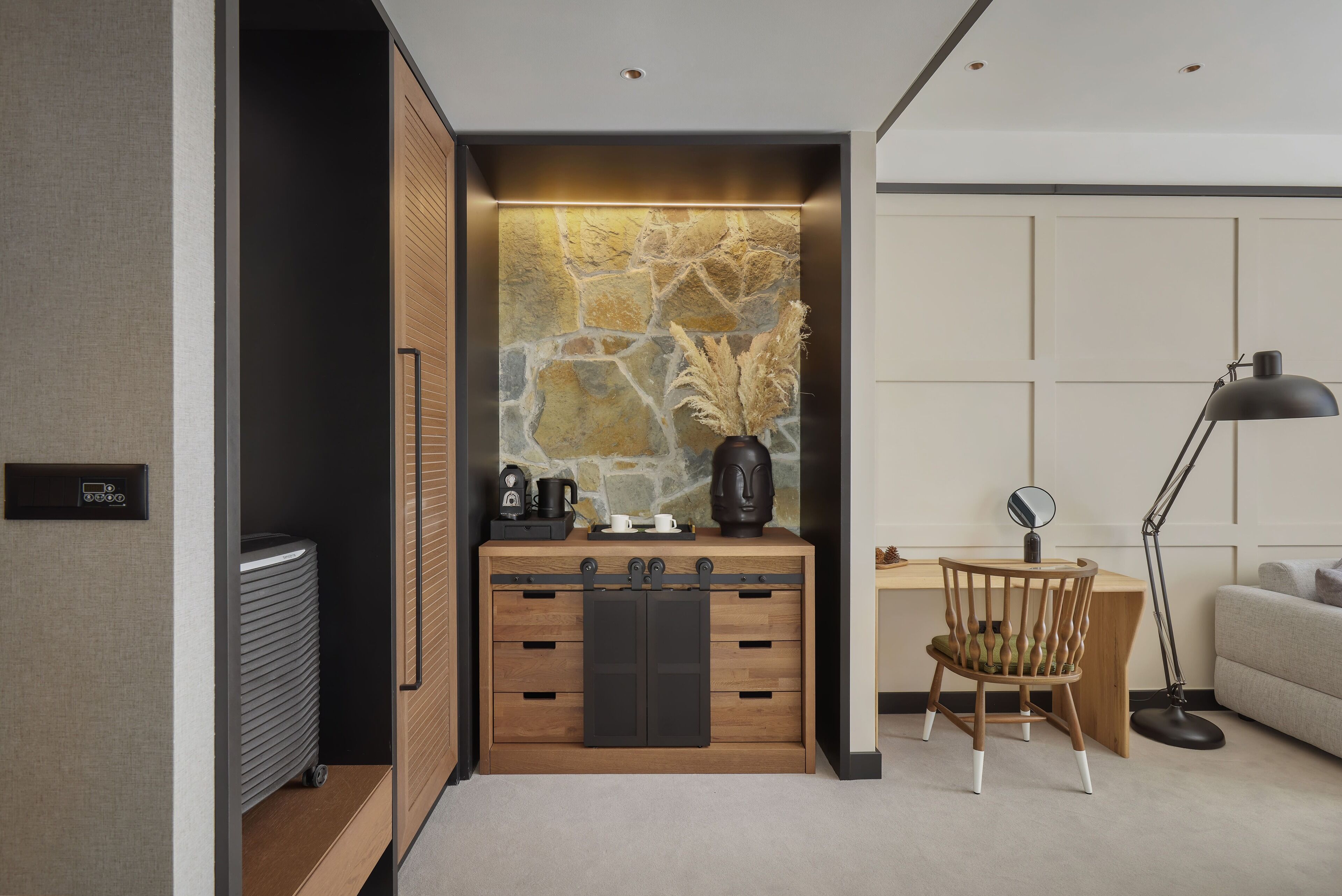 A modern room with a built-in wardrobe, a desk with a chair, and a sofa.