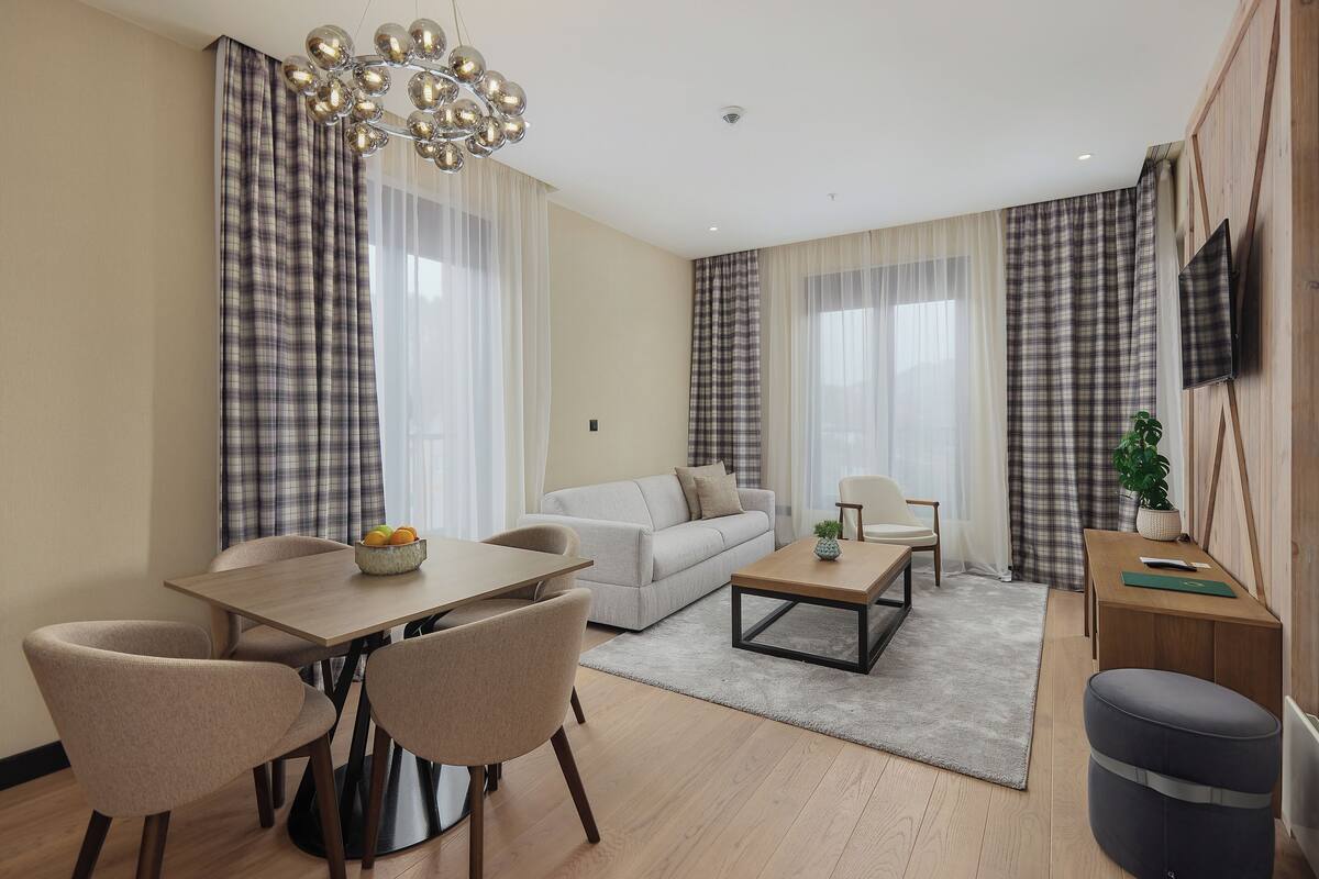 A modern living room with a sofa, coffee table, dining table, and chairs.