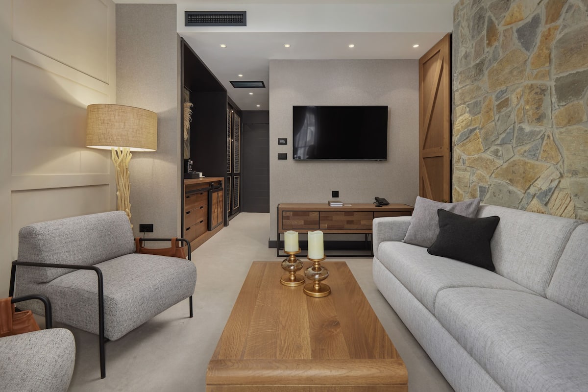 A modern living room with a grey sofa, a wooden coffee table, and a lamp.