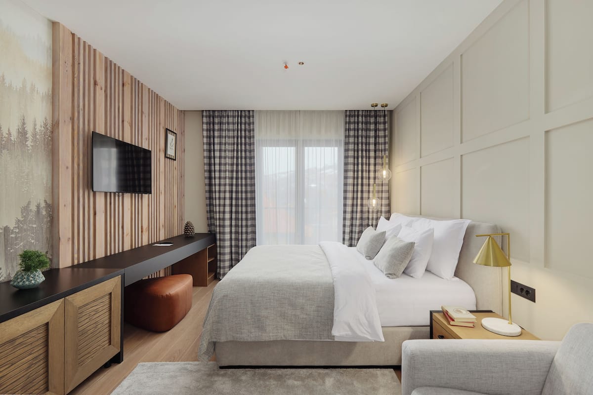 A modern bedroom with a bed, bedside table, lamp, and a TV mounted on the wall.