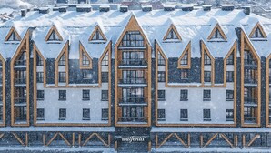 A hotel with a symmetrical facade, multiple balconies, and a snowy mountain backdrop. - Wulfenia Hotel & Spa (Kolašin)