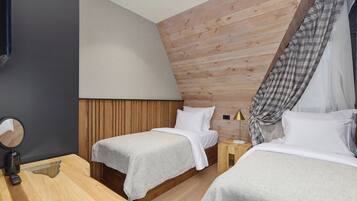 Une chambre moderne avec deux lits, des murs recouverts de panneaux en bois, une petite table de chevet avec une lampe et un miroir sur le côté gauche.