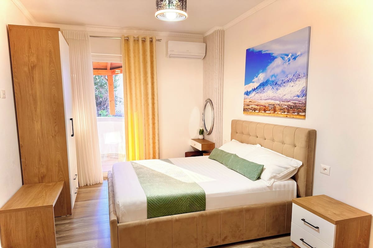 Un dormitorio con cama, mesitas de noche, un espejo y un cuadro en la pared.
