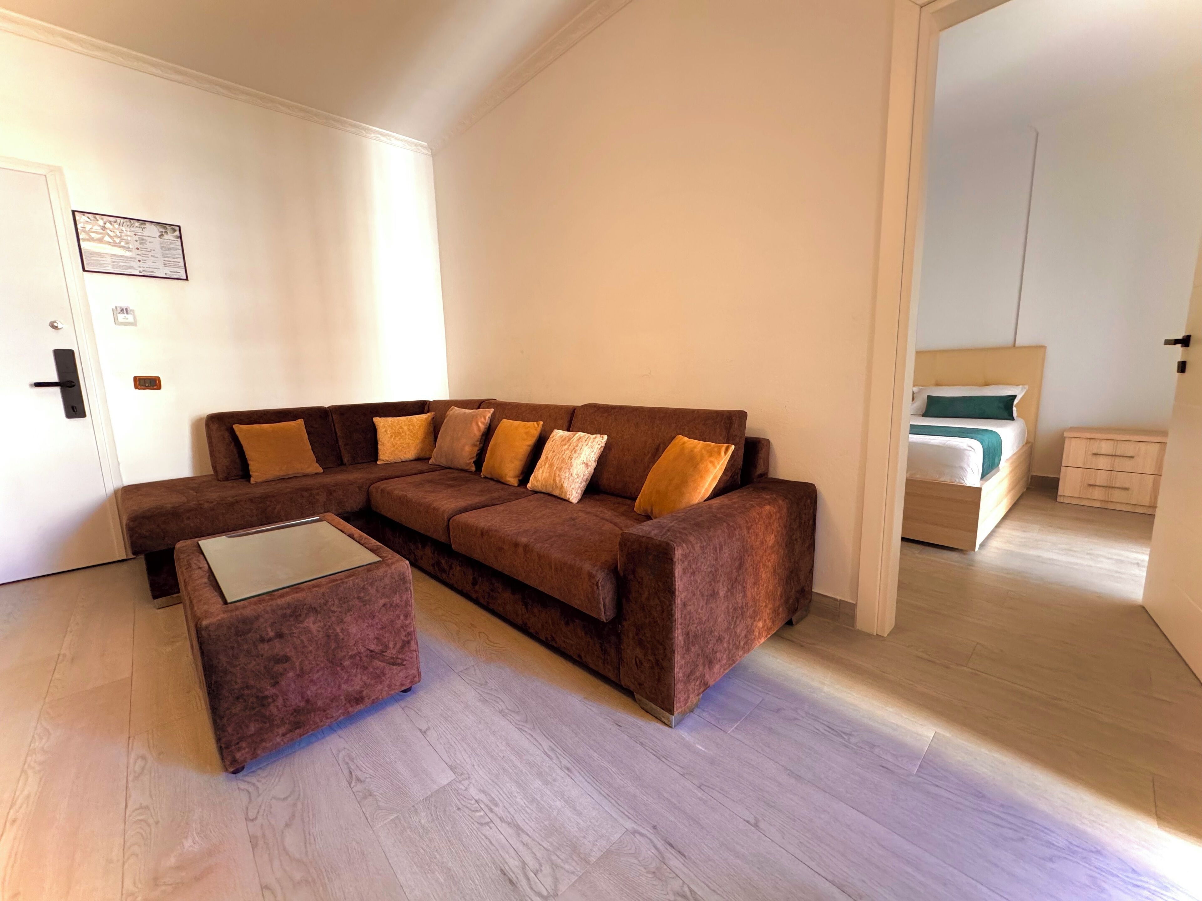 A modern living room with a brown sectional sofa, a glass coffee table, and a wooden floor.
