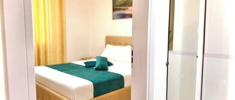 A bedroom with a bed, a wardrobe, and a painting on the wall.