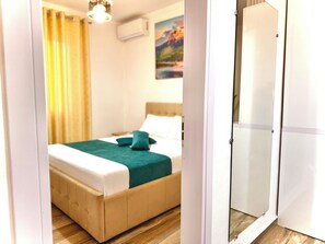 A bedroom with a bed, a wardrobe, and a painting on the wall. - Elite Apartments (Durrës)