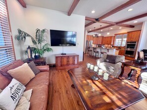 A living room with a brown leather couch, a wooden coffee table, and a TV mounted on the wall.