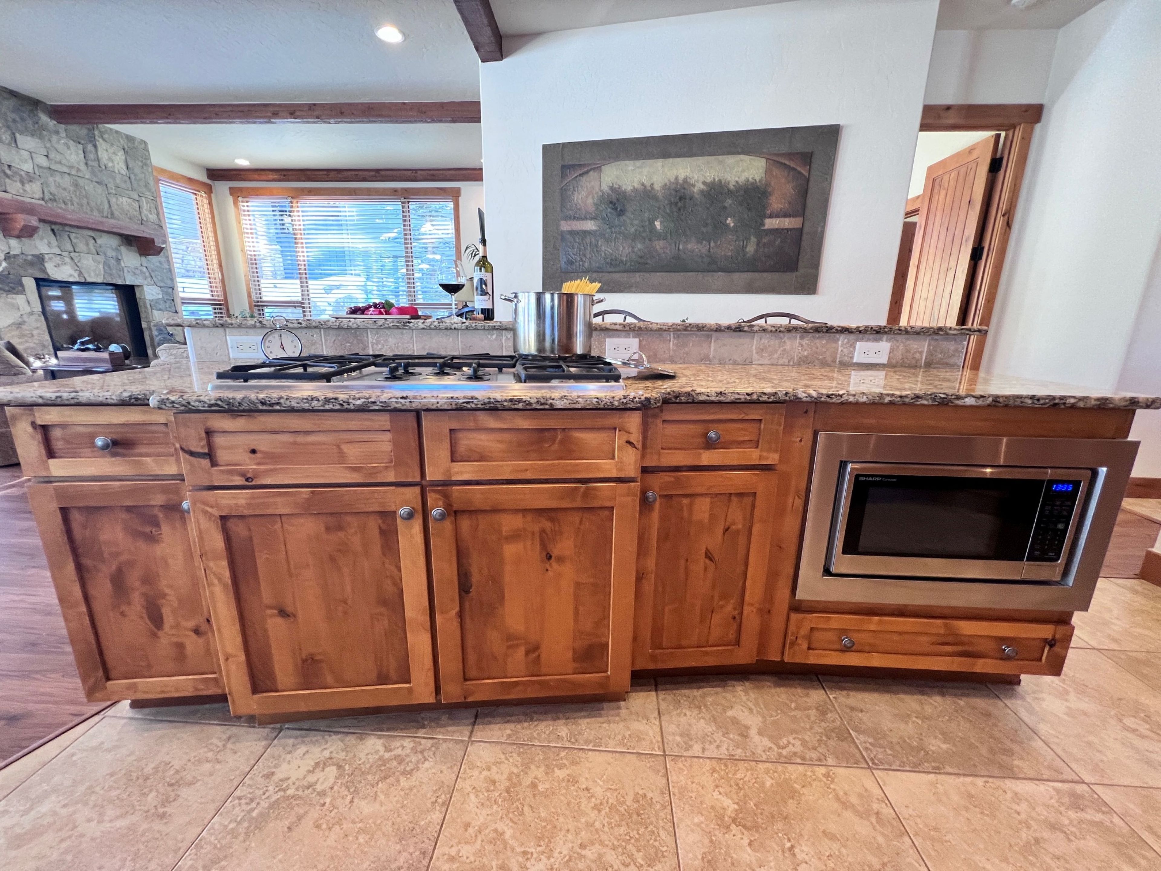 A kitchen with a granite countertop, wooden cabinets, a built-in oven, and a stone fireplace.