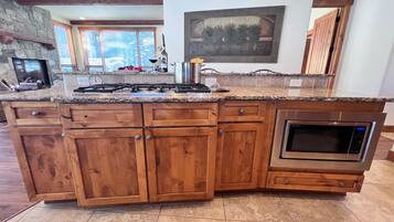 A kitchen with a granite countertop, wooden cabinets, a built-in oven, and a stone fireplace.