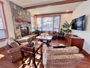 A living room with a stone fireplace, a large TV, and a comfortable seating area.