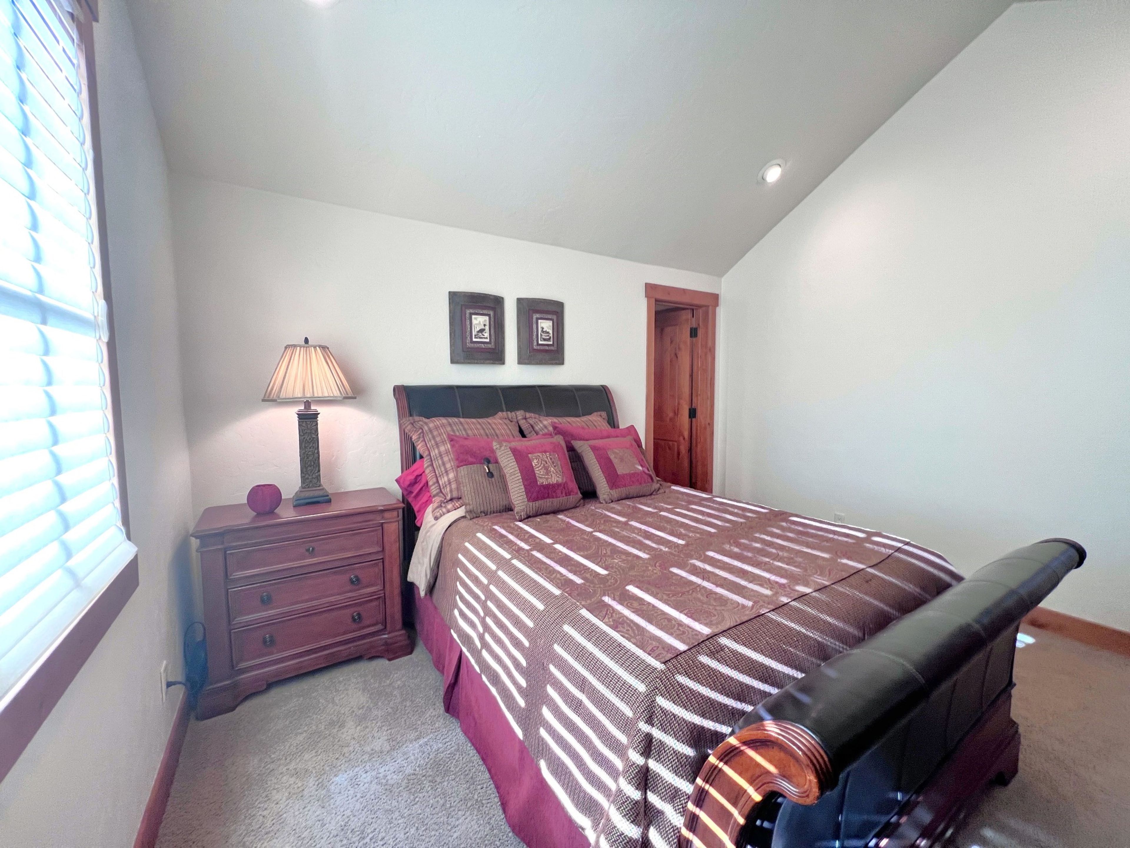 A bedroom with a bed, nightstand, lamp, and a door.