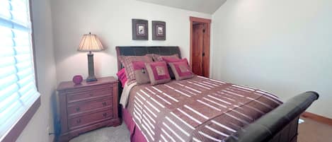 A bedroom with a bed, nightstand, lamp, and a door.