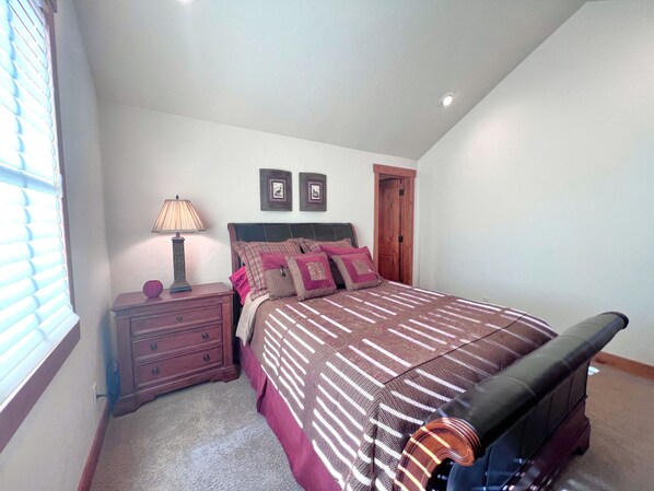 A bedroom with a bed, nightstand, lamp, and a door. - Eagles Nest • Mtn Views • Dog-Friendly • Ev Charger • Ski/Hike (Silverthorne)