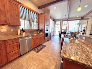 A kitchen with wooden cabinets, granite countertops, stainless steel appliances, and a dining area with a view. - Eagles Nest • Mtn Views • Dog-Friendly • Ev Charger • Ski/Hike (Silverthorne)