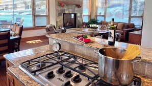 A modern kitchen with a gas stove, granite countertops, and a stone fireplace. - Eagles Nest • Mtn Views • Dog-Friendly • Ev Charger • Ski/Hike (Silverthorne)