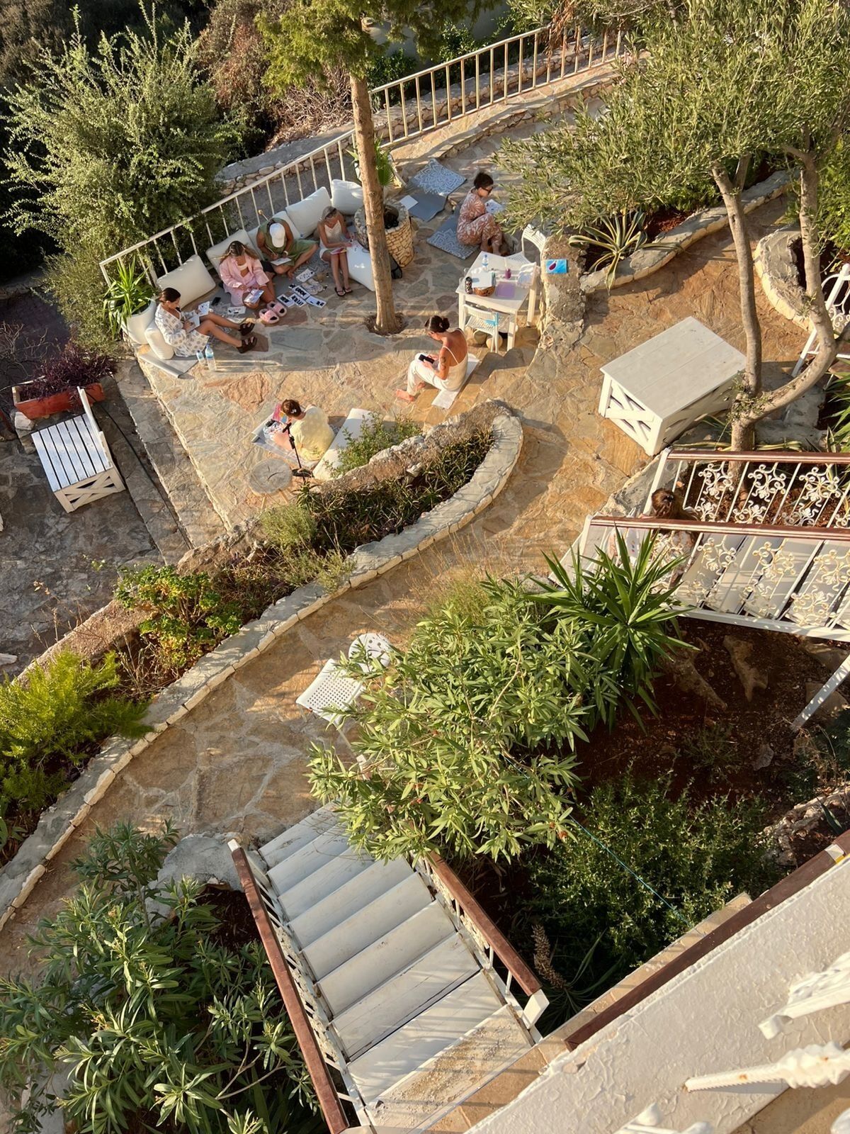 An outdoor patio area with stone flooring, seating arrangements, and various plants.