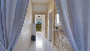 A corridor with a view to an outdoor area, a door, and a small shelf with items. - 4204 Villetta Delle More by Barbarhouse (Melendugno)