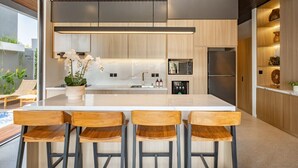Cozinha moderna com uma ilha grande, banquetas e eletrodomésticos embutidos.
