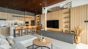 Uma sala de estar moderna com sofá, mesa de centro e televisão fixada numa parede de madeira.