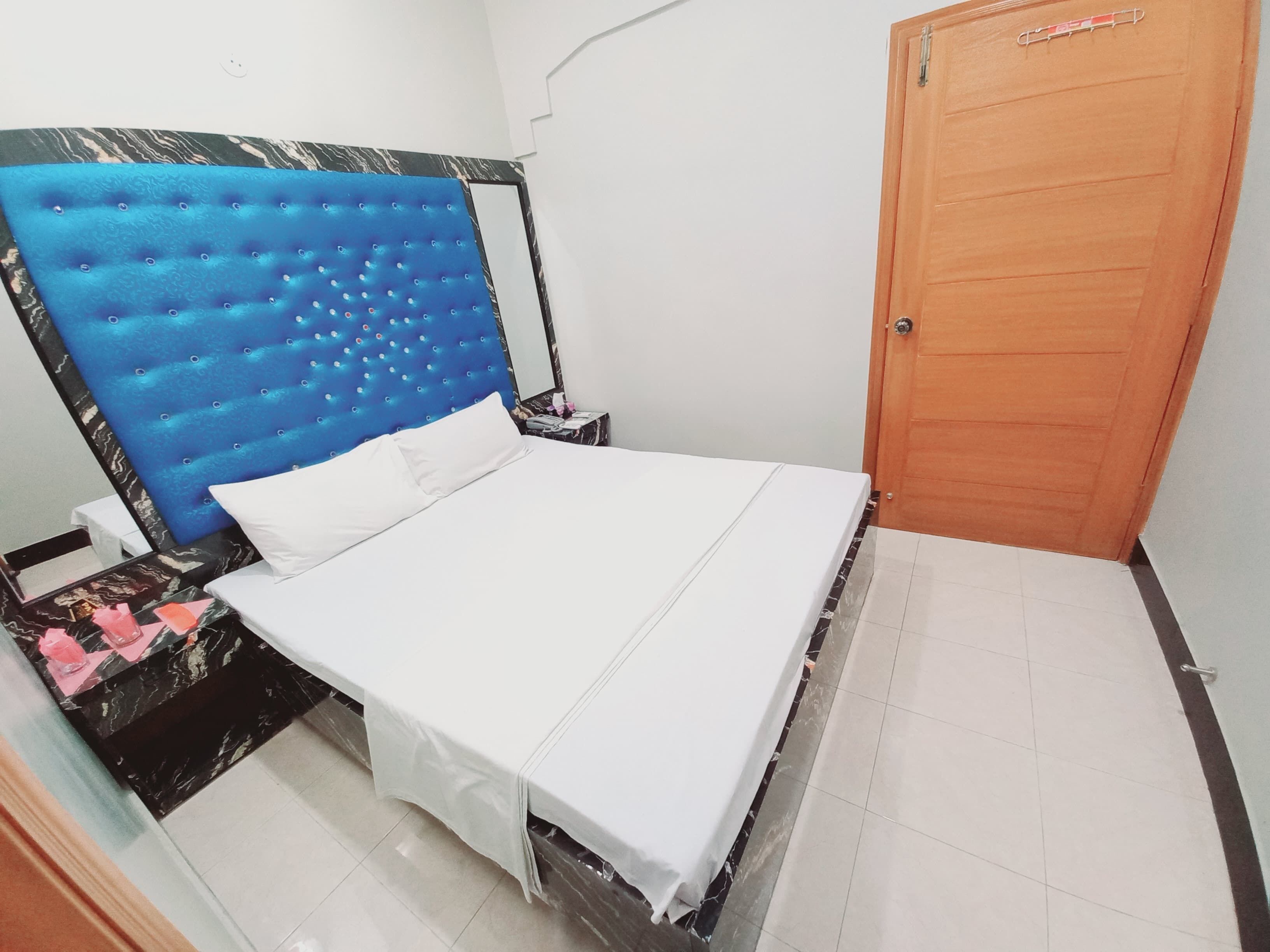 A bedroom with a bed, a nightstand, a wooden door, and a marble-patterned headboard.
