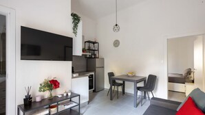 Un espacio habitable compacto con kitchenette, comedor y sofá con cojines rojos.