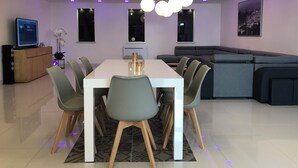 Un espace repas moderne avec une table blanche, des chaises grises et un buffet en bois.