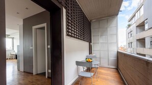A modern apartment with a balcony, a dining area with a table and chairs, and a view of the cityscape.