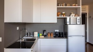 A modern kitchen with white cabinetry, a built-in oven, a refrigerator, and various kitchen appliances.