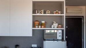 A kitchen with white cabinets, a built-in oven, and a shelf with decorative items including a 'cuisine' sign, a coffee maker, and small plants.