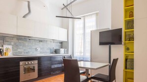 A modern kitchen with a built-in oven, a microwave, and a dining area with a table and chairs.