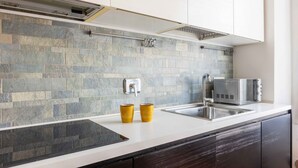 A modern kitchen with a stone backsplash, a built-in microwave, and a stainless steel sink.