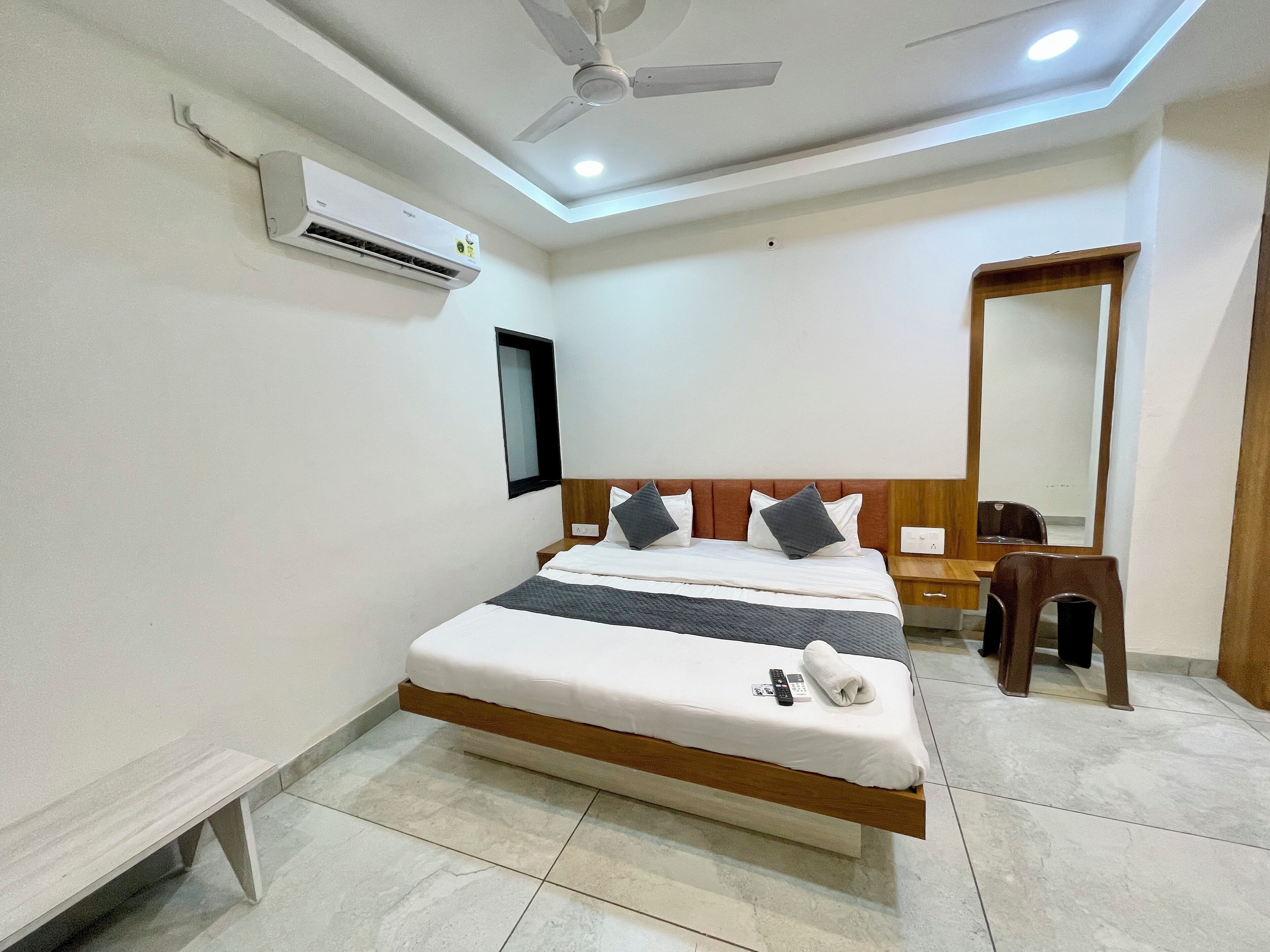 Una habitación de hotel con cama, escritorio, silla, ventilador de techo y aire acondicionado.