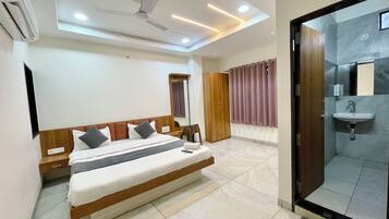 A modern hotel room with a large bed, a wardrobe, a bathroom with a sink, and a ceiling fan.