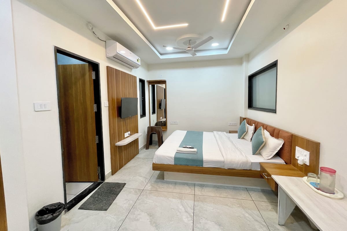 Ein modernes Hotelzimmer mit Bett, Schreibtisch, Spiegel, Fernseher und Klimaanlage.