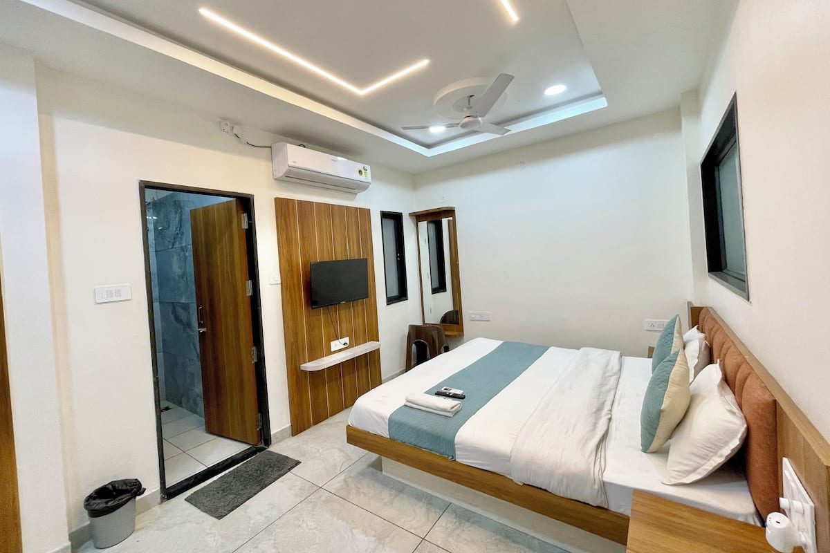 Ein modernes Hotelzimmer mit Bett, Fernseher, Deckenventilator und Klimaanlage.