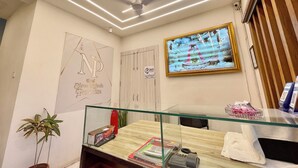 Zona de recepción de un hotel con un diseño de techo moderno, una obra de arte enmarcada en la pared y un mostrador de recepción con varios objetos.