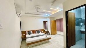 Habitación de hotel moderna con una cama grande, un ventilador de techo y una puerta corrediza de vidrio que da a un baño.