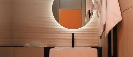 A modern bathroom with a round mirror, a sink, and a towel rack.