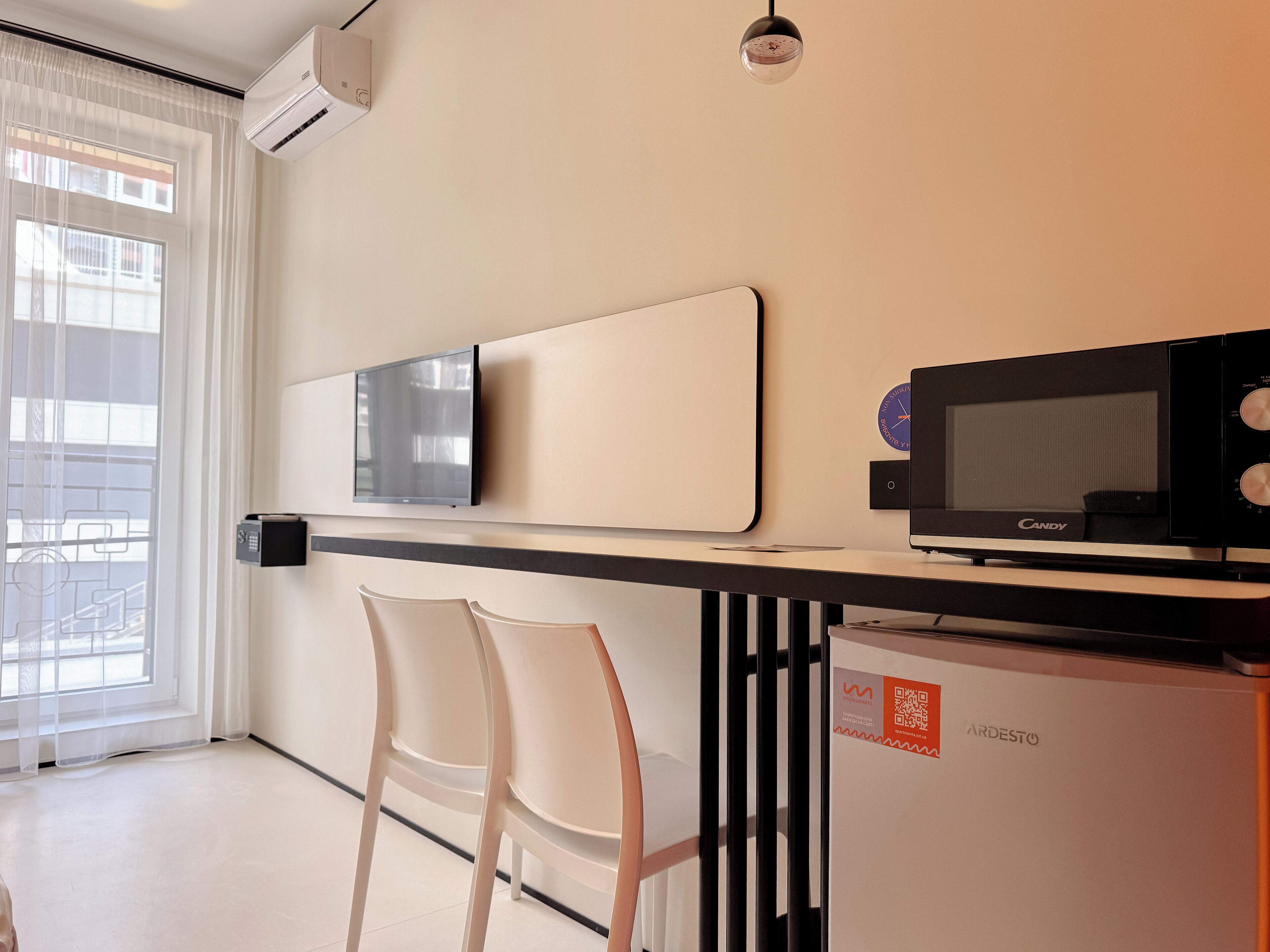 Una kitchenette moderna con microondas, televisión de pantalla plana y un refrigerador pequeño.