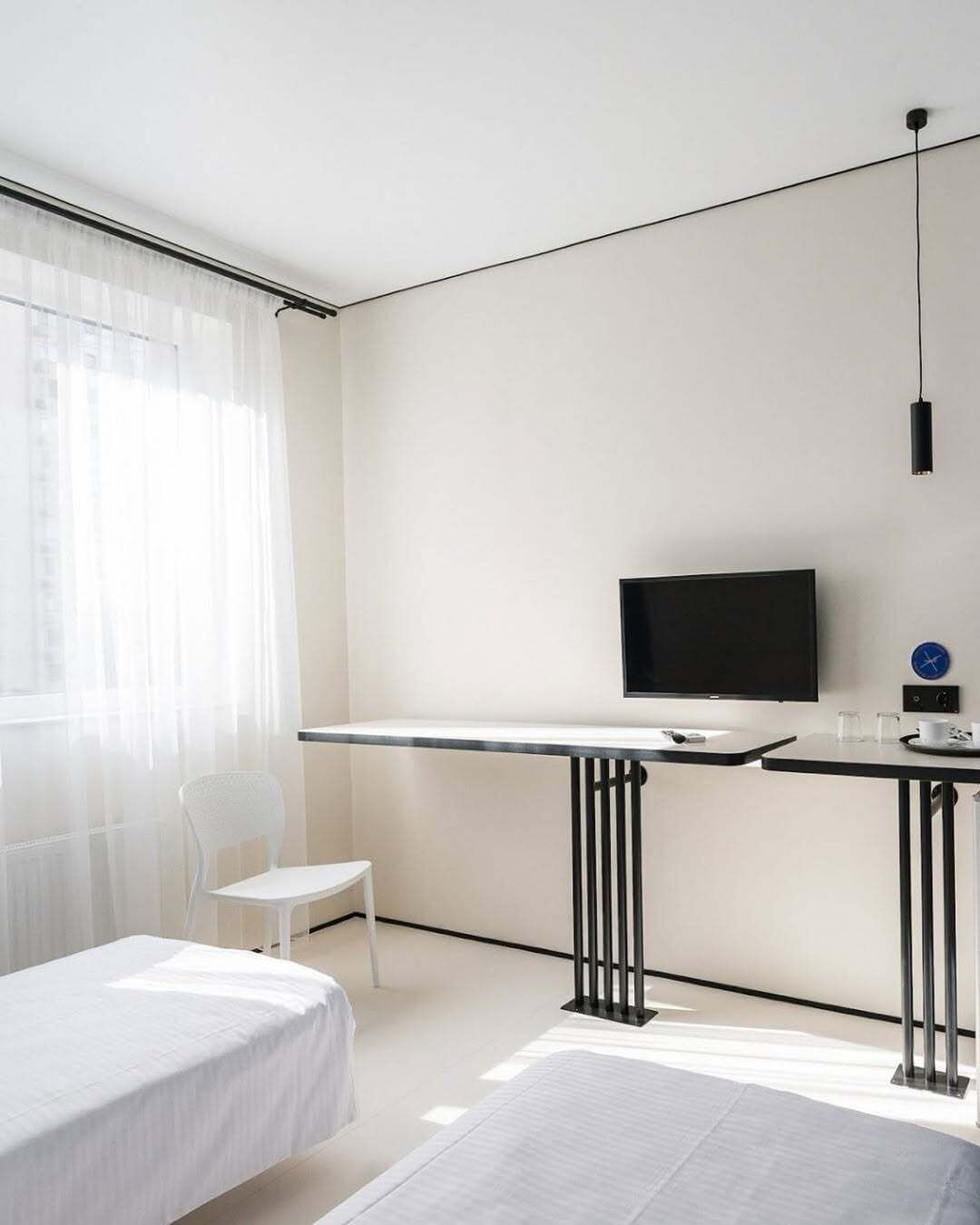 Een strak ingerichte hotelkamer met een bed, een bureau, een stoel en een televisie.