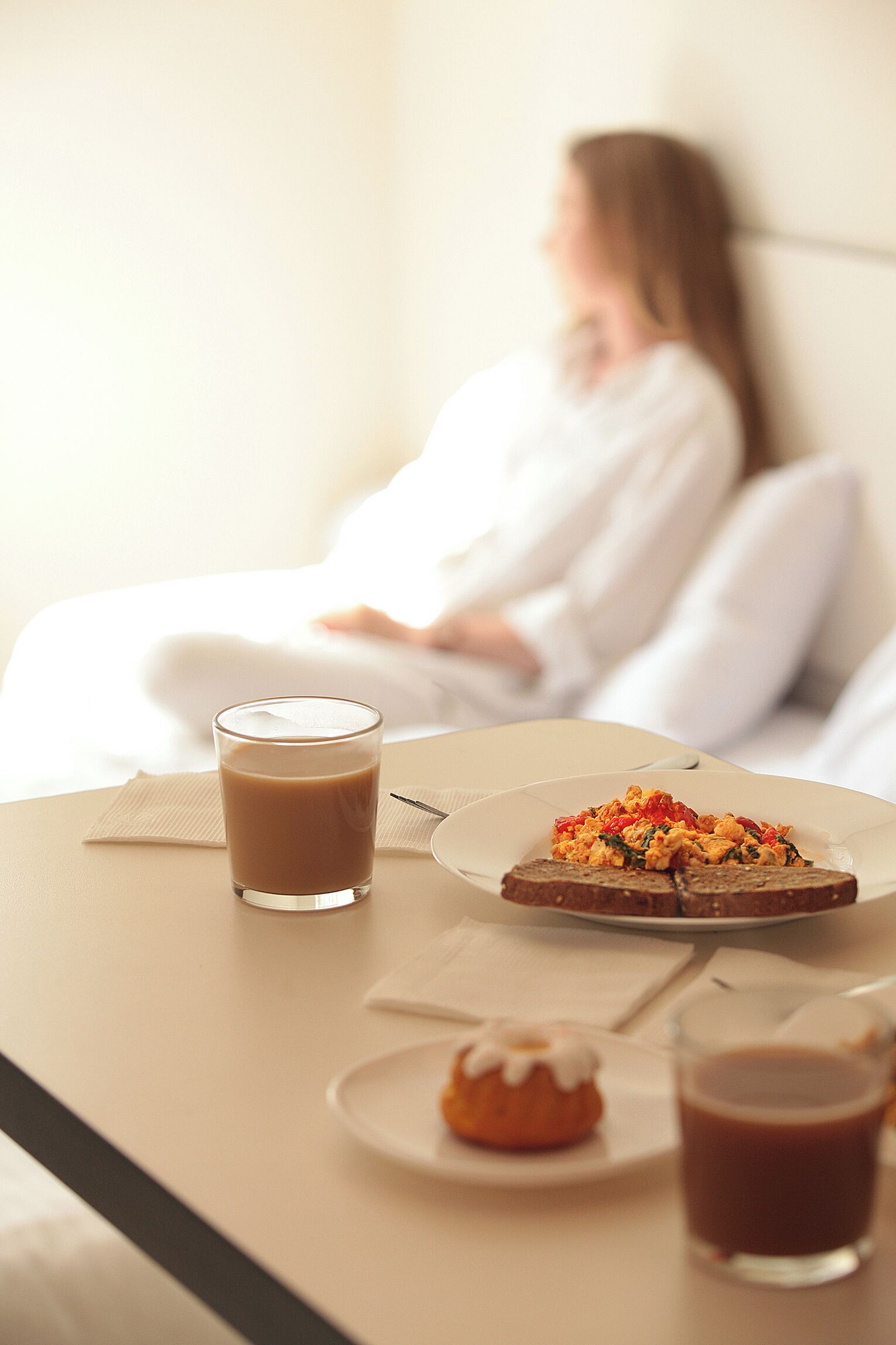 Een ontbijttafel met een kop koffie, een bord roerei en een gebakje.