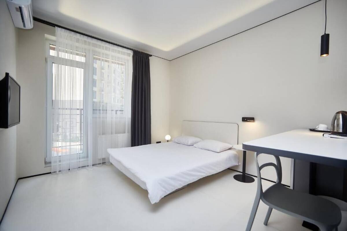 Una camera d'albergo moderna con un letto, una scrivania e una sedia.