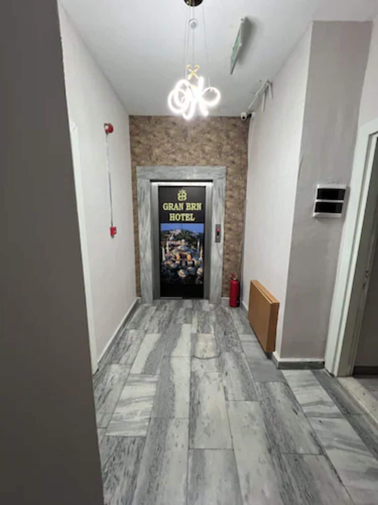 A hallway with a marble floor leading to a door labeled "GRAN BRN HOTEL".