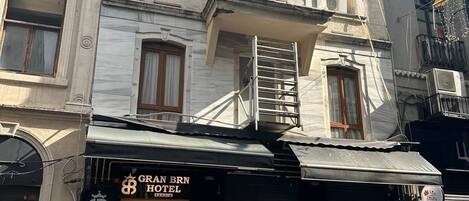 A hotel with a black awning and a sign reading "GRAN BRN HOTEL".