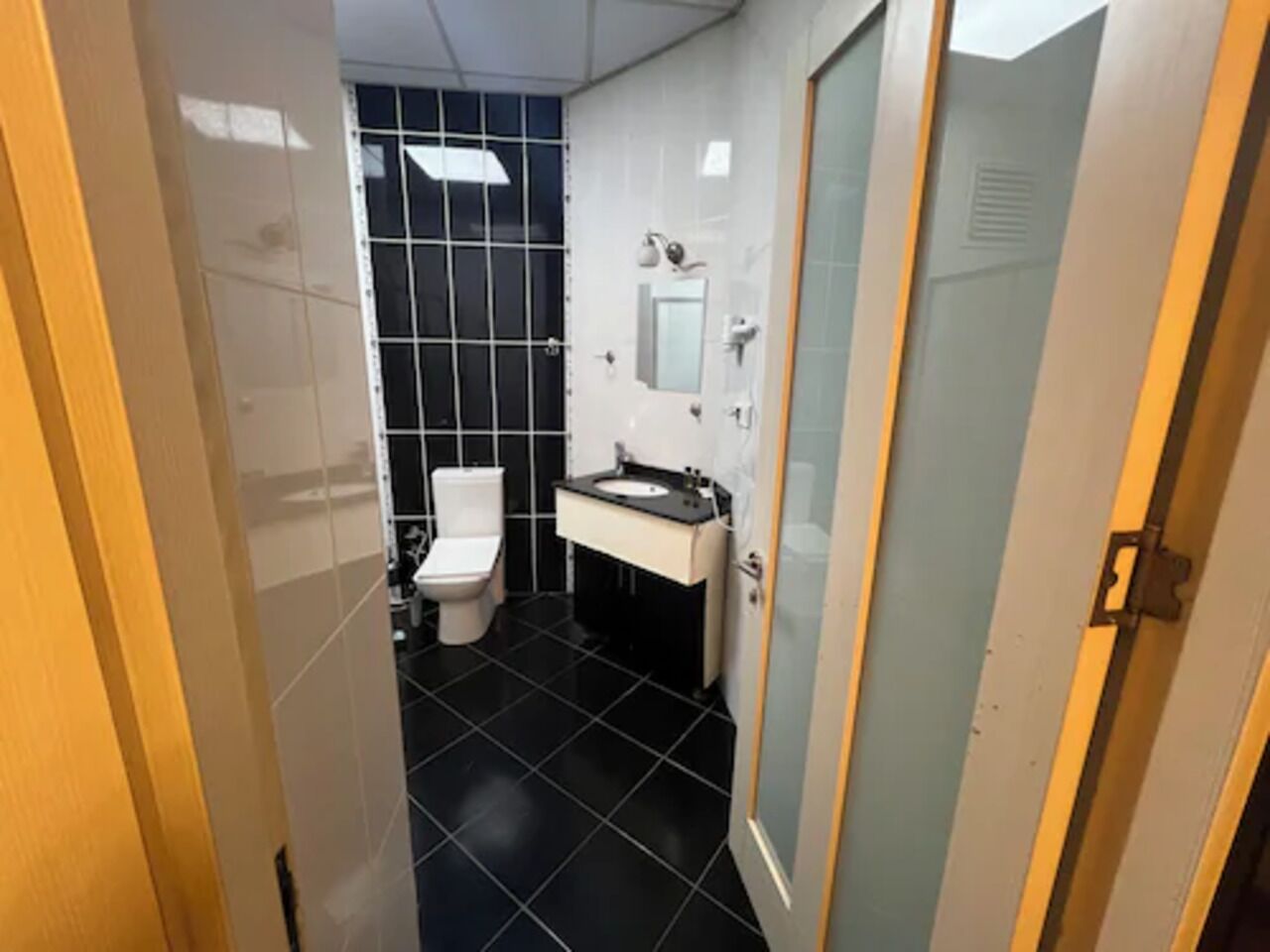 Un bany petit amb vàter, un lavabo i un mirall.
