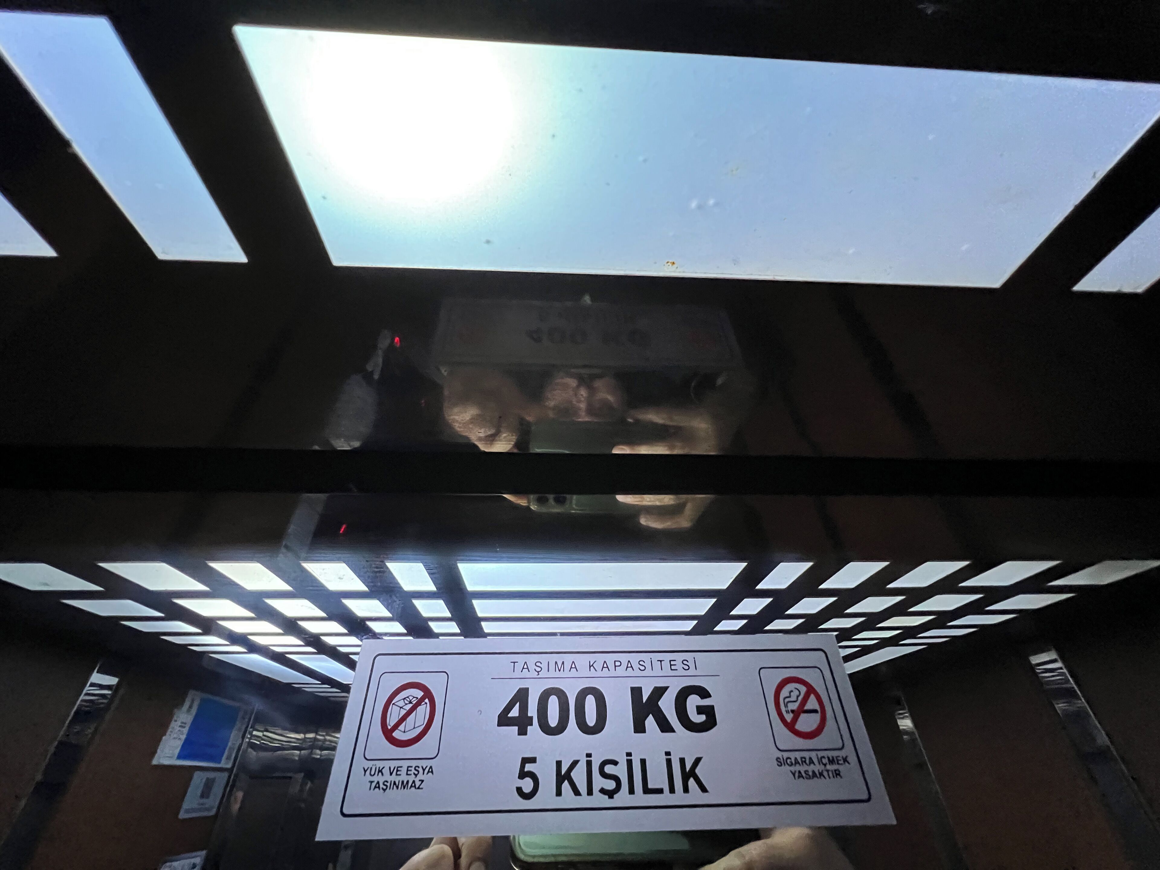 Techo con tragaluces y un letrero que indica un límite de peso de 400 KG y un límite de altura de 5 kİŞİLİK.