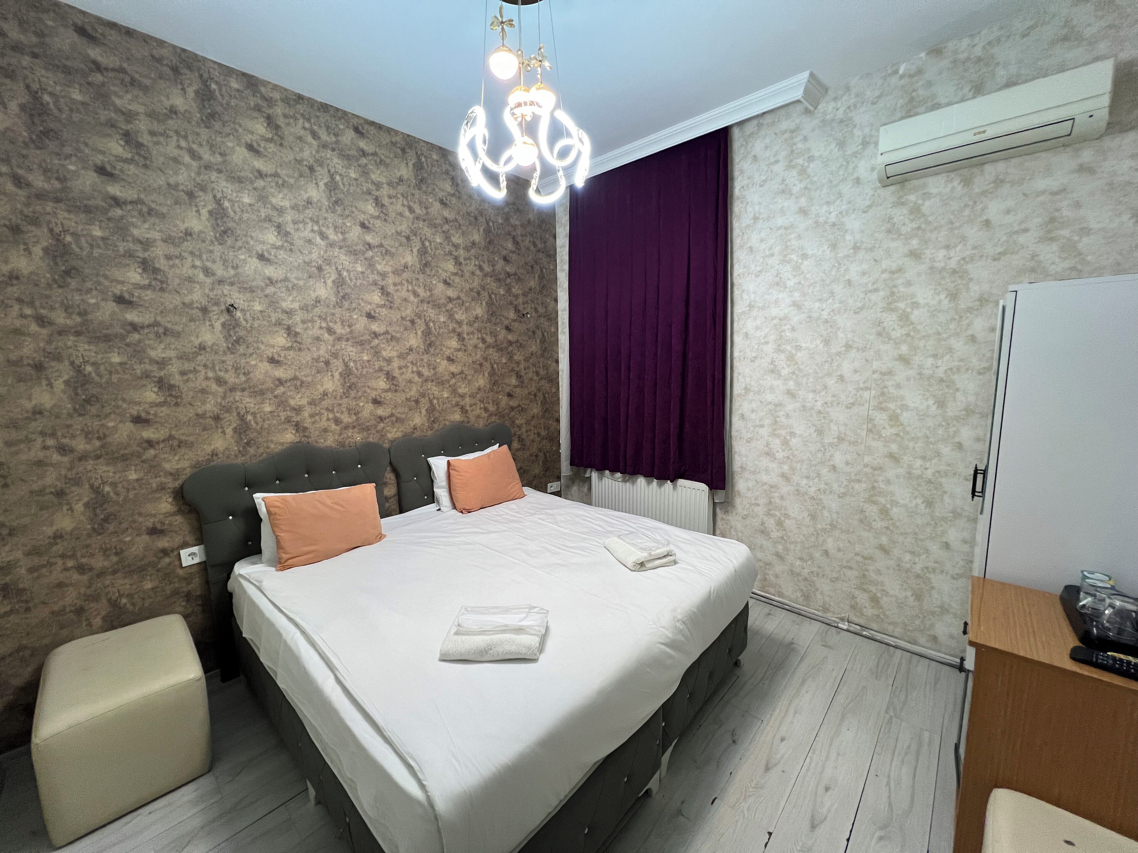 A bedroom with a bed, a nightstand, a dresser, and a ceiling light fixture.