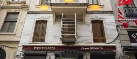 A building with a storefront labeled "Beyaz Lokanta" featuring a traditional design with a balcony and a staircase leading to the entrance.